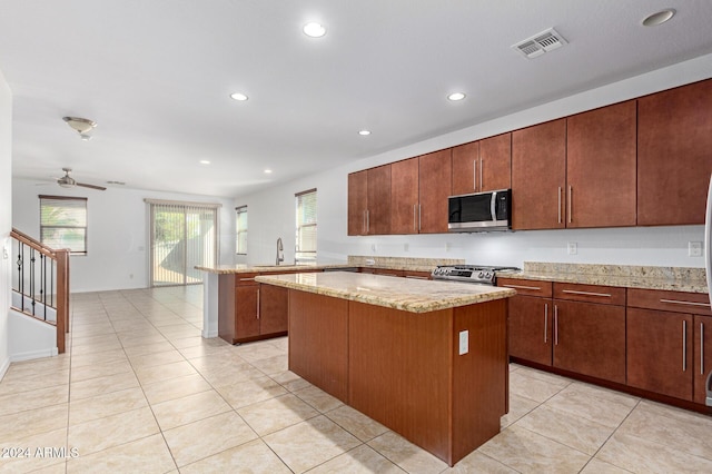 kitchen featuring ceiling fan, a center island, kitchen peninsula, light tile patterned floors, and appliances with stainless steel finishes