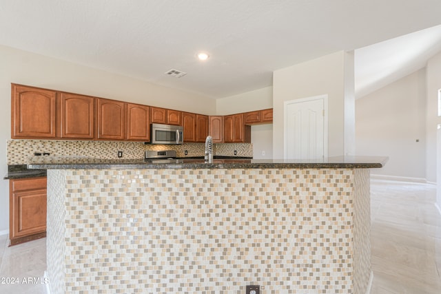 kitchen featuring a center island with sink, backsplash, appliances with stainless steel finishes, and light tile patterned flooring