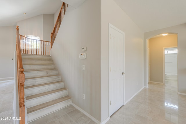 staircase with lofted ceiling and tile patterned flooring