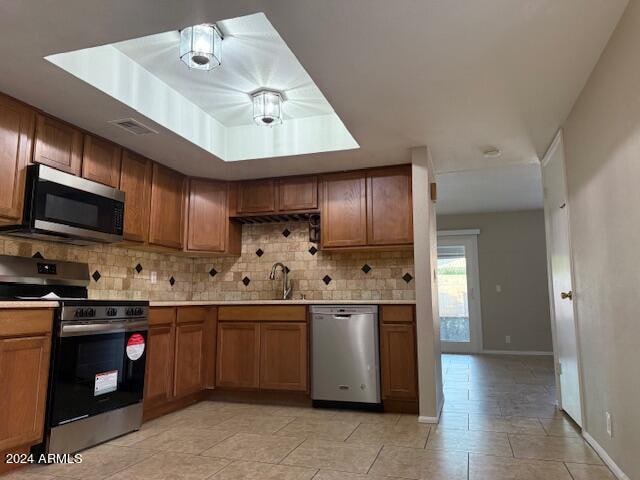 kitchen with light tile patterned floors, appliances with stainless steel finishes, backsplash, and sink