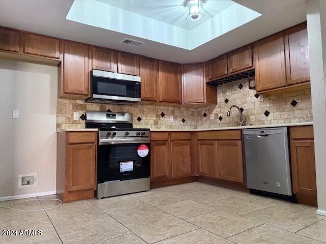 kitchen with sink, stainless steel appliances, light tile patterned floors, and decorative backsplash