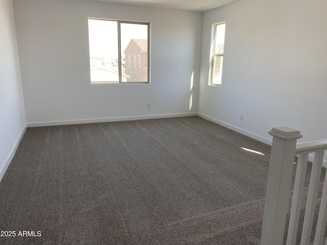 unfurnished room featuring dark colored carpet and baseboards