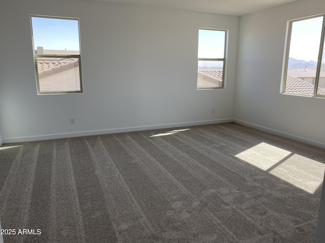 carpeted empty room with a healthy amount of sunlight and baseboards