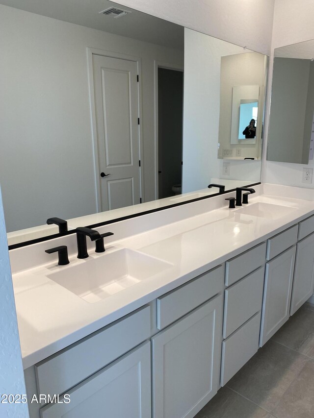 bathroom with a sink, visible vents, double vanity, and tile patterned floors