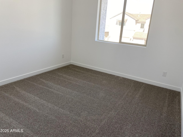 empty room with dark carpet and baseboards