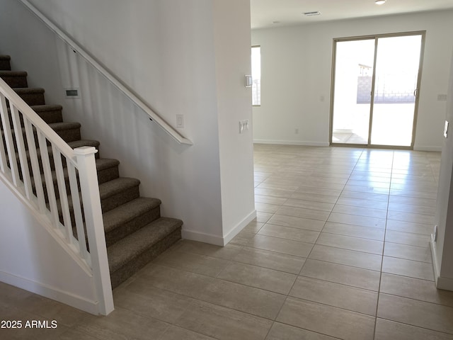 staircase featuring tile patterned flooring, baseboards, and a wealth of natural light