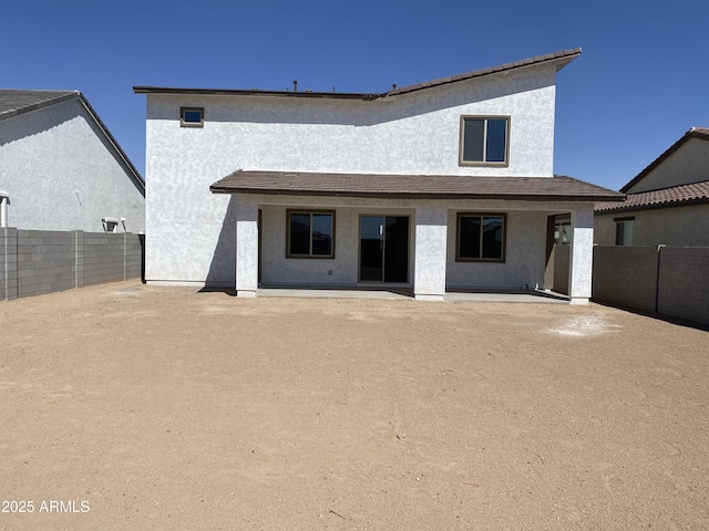 rear view of house with stucco siding and a fenced backyard