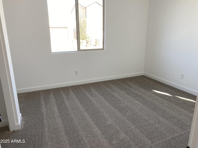 empty room featuring baseboards and dark colored carpet