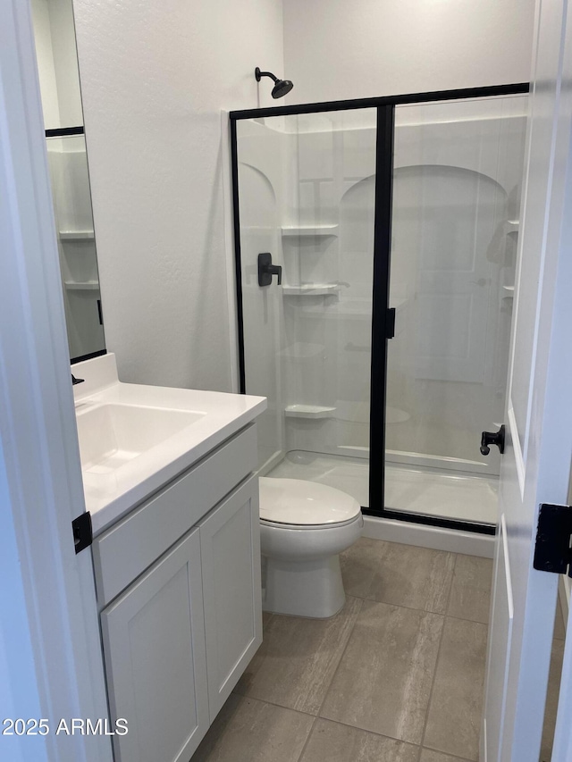 bathroom featuring a shower stall, toilet, and vanity