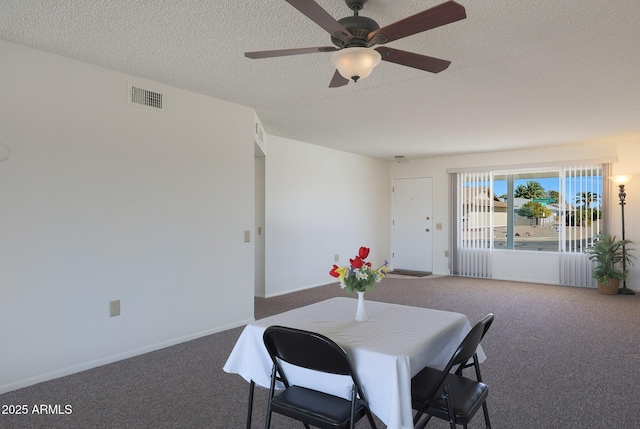 dining room with ceiling fan, dark carpet, and a textured ceiling