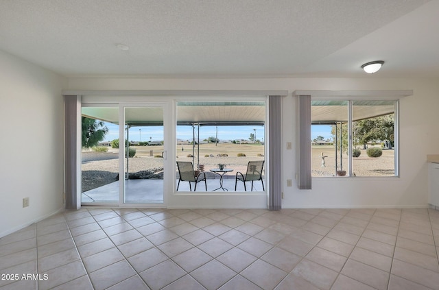 empty room with a textured ceiling and light tile patterned flooring