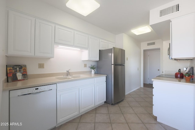 kitchen with light tile patterned flooring, sink, stainless steel fridge, white cabinets, and white dishwasher