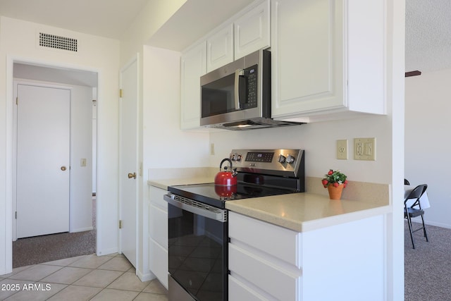 kitchen featuring appliances with stainless steel finishes, light tile patterned floors, a textured ceiling, and white cabinets