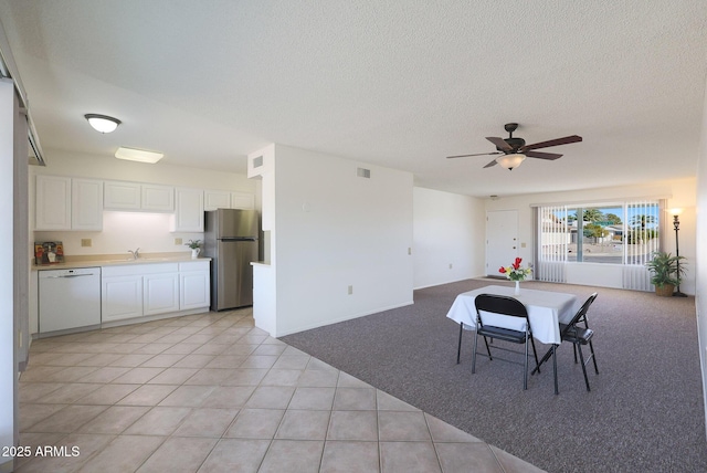 dining area featuring ceiling fan, sink, a textured ceiling, and light tile patterned floors