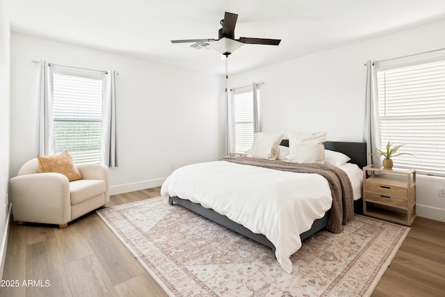 bedroom with multiple windows, wood finished floors, and baseboards