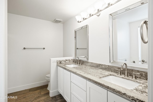 full bath featuring toilet, wood finished floors, baseboards, and a sink