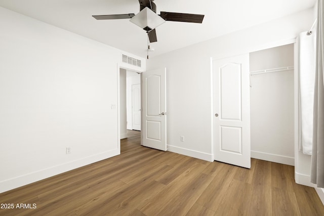 unfurnished bedroom featuring wood finished floors, visible vents, a closet, and baseboards