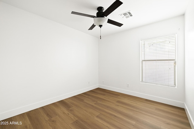 spare room featuring visible vents, ceiling fan, baseboards, and wood finished floors