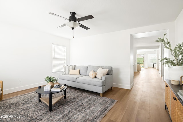 living area with baseboards, light wood-style floors, and ceiling fan