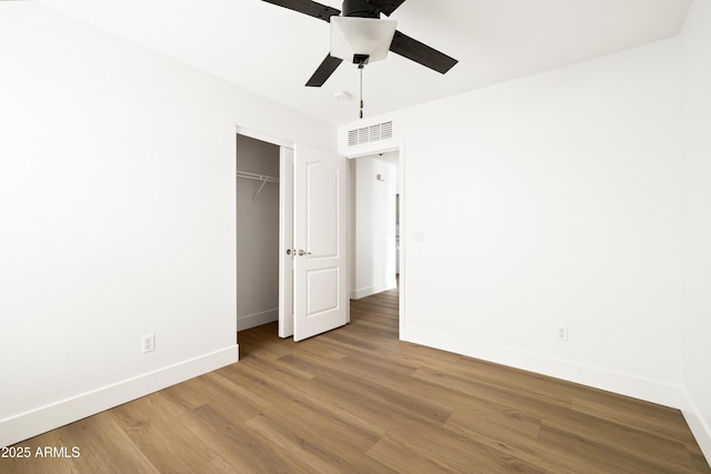 unfurnished bedroom featuring visible vents, baseboards, wood finished floors, a closet, and a ceiling fan