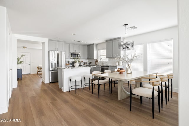 dining area with visible vents, light wood-type flooring, and baseboards