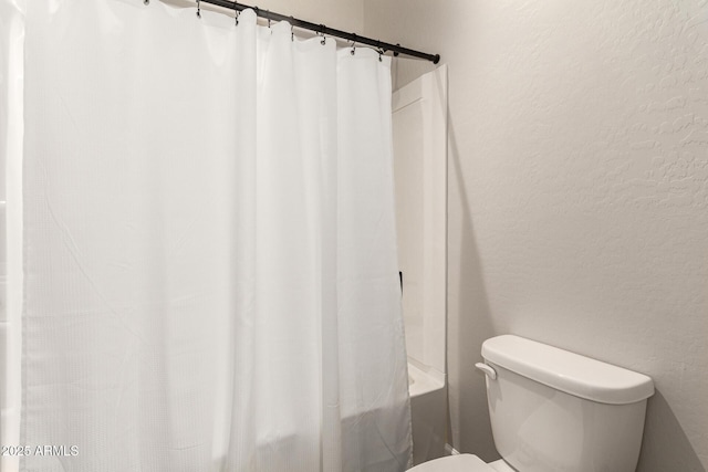 full bath featuring shower / bathtub combination with curtain, toilet, and a textured wall