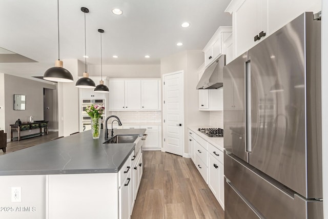 kitchen featuring under cabinet range hood, a sink, backsplash, white cabinetry, and stainless steel appliances