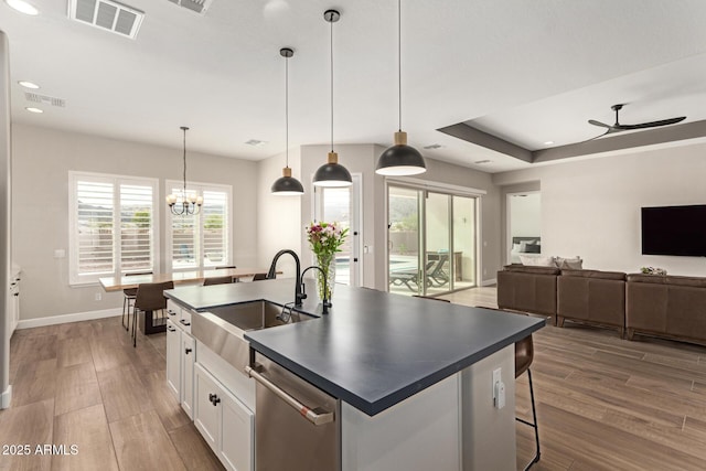 kitchen with visible vents, a sink, dark countertops, wood finished floors, and dishwasher