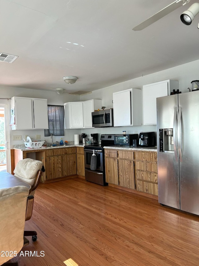 kitchen featuring sink, white cabinetry, light hardwood / wood-style flooring, and stainless steel appliances