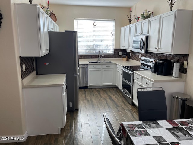 kitchen featuring white cabinetry, sink, decorative backsplash, appliances with stainless steel finishes, and dark hardwood / wood-style flooring