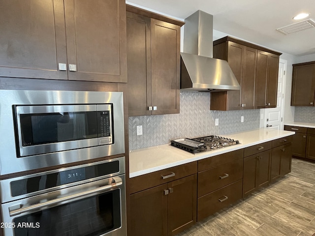 1840 S Follett Way, Gilbert, AZ 85295 - kitchen featuring stainless steel appliances, wall chimney range hood, dark brown cabinets, light countertops, and backsplash