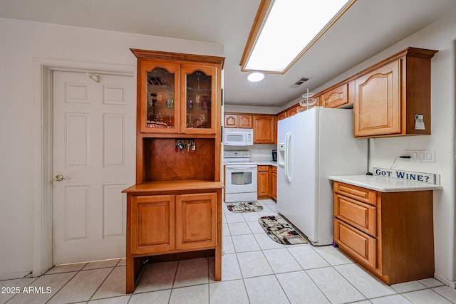 kitchen featuring white appliances, brown cabinetry, glass insert cabinets, light countertops, and light tile patterned flooring