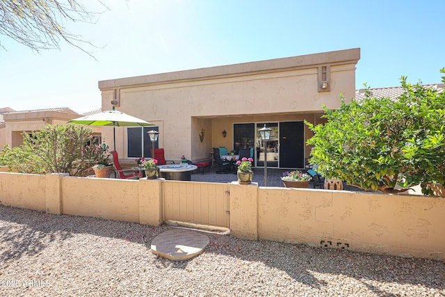 back of house featuring fence private yard, a patio area, and stucco siding