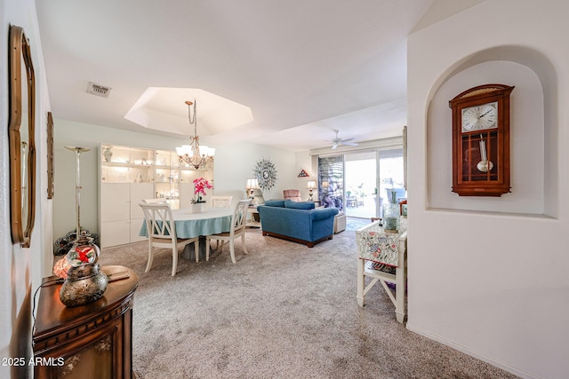 dining room featuring ceiling fan with notable chandelier, a tray ceiling, carpet, and visible vents