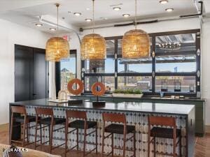 bar with a wealth of natural light, decorative light fixtures, and hardwood / wood-style flooring