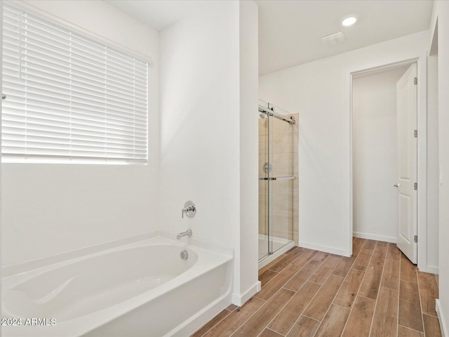 bathroom featuring plus walk in shower and wood-type flooring