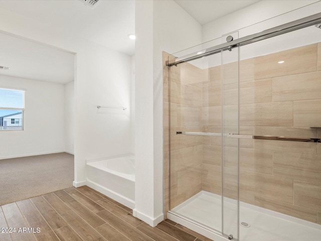 bathroom featuring hardwood / wood-style floors and plus walk in shower