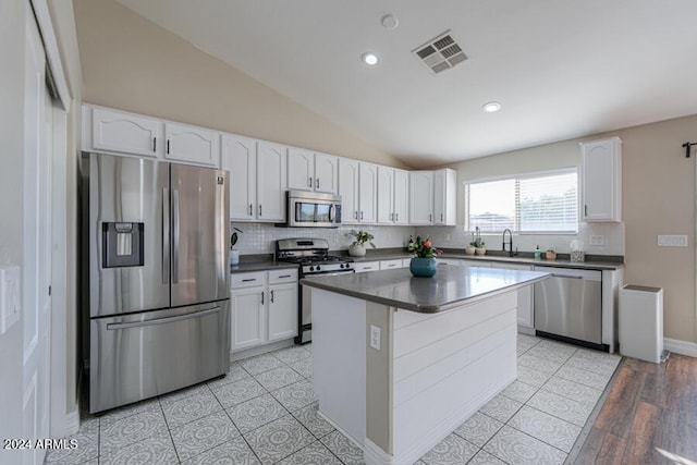 kitchen featuring white cabinetry, sink, lofted ceiling, a kitchen island, and appliances with stainless steel finishes