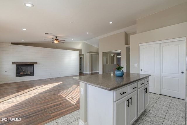 kitchen featuring lofted ceiling, dark stone counters, ceiling fan, light tile patterned floors, and a kitchen island