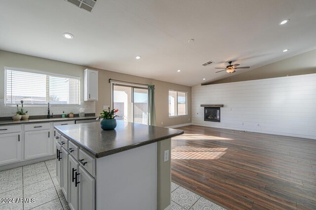 kitchen featuring a center island, lofted ceiling, ceiling fan, decorative backsplash, and white cabinetry