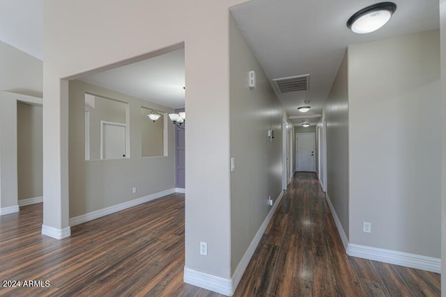 hallway with dark hardwood / wood-style floors and an inviting chandelier