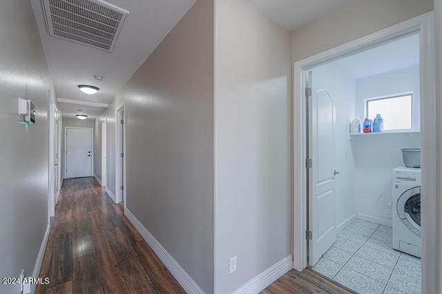 corridor with hardwood / wood-style flooring and washer / dryer