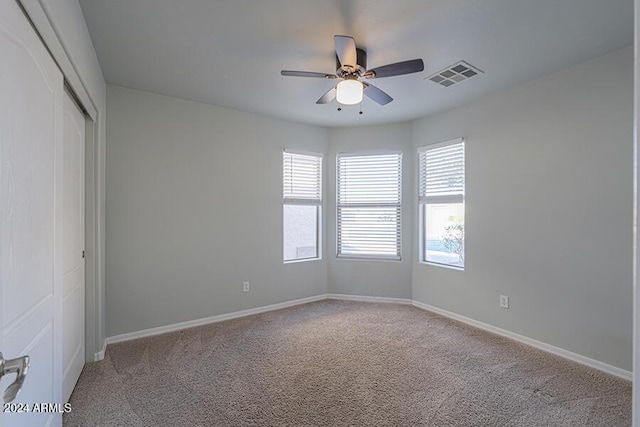 carpeted spare room featuring ceiling fan