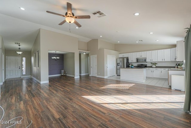 interior space featuring ceiling fan with notable chandelier, stainless steel appliances, hardwood / wood-style flooring, high vaulted ceiling, and white cabinetry