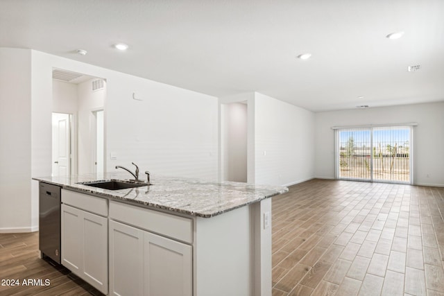 kitchen with light stone countertops, stainless steel dishwasher, sink, a center island with sink, and white cabinetry