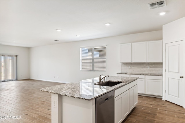 kitchen with light stone counters, stainless steel dishwasher, sink, a center island with sink, and white cabinetry