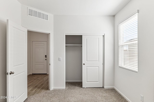 unfurnished bedroom with a closet and light colored carpet