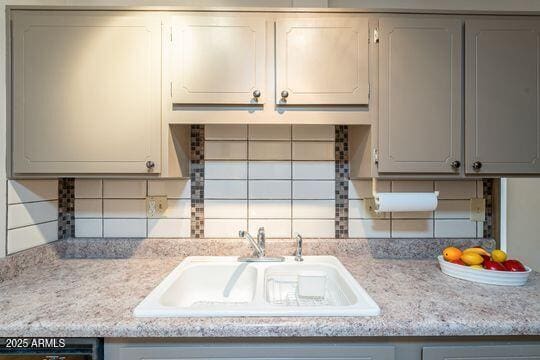 kitchen with sink, dishwasher, gray cabinets, light stone countertops, and decorative backsplash