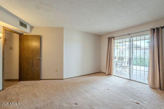 empty room with a textured ceiling and light colored carpet