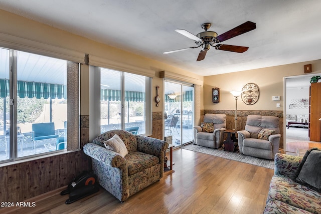 living room featuring light hardwood / wood-style floors, a wealth of natural light, wood walls, and ceiling fan